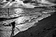 A fine art photo in black and white of a boy splashing in winter waves on Felixstowe beach